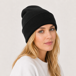 A woman with blonde hair wearing a black ribbed knit beanie hat and a white sweatshirt, photographed against a plain light background.