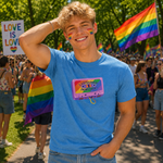 A smiling young man at a Pride parade wearing a bright blue t-shirt with a retro cassette graphic that reads 'I JUST LATELY KNOW I'M MARRIED' and jeans, with rainbow flags and a crowd in the background.