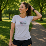 A woman wearing a light grey t-shirt with a 'Kirkcaldy Park's Running Festival' graphic, standing on a park path.