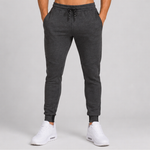 Dark grey heather jogger sweatpants with a drawstring waist and elastic cuffs, shown on a model from the waist down wearing white sneakers against a light grey studio background.