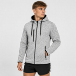 A man wearing a light grey heather zip-up hoodie with black drawstrings, black trim, and black athletic shorts, photographed against a plain light grey studio background.