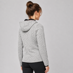 A woman shown from the back wearing a light grey heathered hooded sweatshirt with black trim, paired with black leggings, against a solid grey studio background.