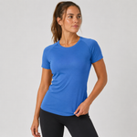 A woman wearing a bright blue short-sleeve athletic t-shirt and black leggings, posing against a light grey studio background.