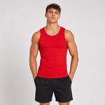 A muscular man wearing a bright red sleeveless tank top and black athletic shorts, standing against a light grey studio background.