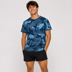 A man wearing a blue camouflage crewneck t-shirt and black shorts, standing against a light gray studio background.