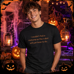 A smiling young man wearing a black graphic t-shirt with orange text that reads, 'I couldn't find a costume so this t-shirt will just have to do.' He is posed against a spooky Halloween-themed background with jack-o'-lanterns, candles, cobwebs, and a dark night sky.