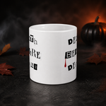 A white ceramic mug with black gothic-style text and a small red blood drop detail, set against a dark, smoky Halloween background with a small black pumpkin and autumn leaves.