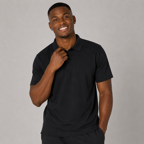 A smiling man wearing a black short-sleeve polo shirt, standing against a plain grey studio background.