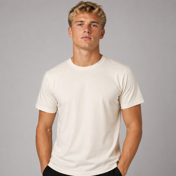A man wearing a plain off-white crewneck t-shirt, standing against a solid grey studio background.