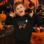 A young boy smiling and posing in a black hoodie with 'Haunted by 6-7' printed on the front, set against a festive Halloween party background with pumpkins and orange decorations.