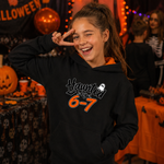 A smiling young woman in a Halloween costume hoodie posing with a peace sign. The hoodie is black with an orange inner hood lining and a graphic on the chest that reads 'Haunted by 6-7' in white and orange lettering with a small white ghost.