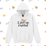 A white pullover hoodie with a graphic on the chest that reads 'I love my Daddies' in black script, featuring two cartoon daddies holding a rainbow heart. The hoodie is displayed on a white background patterned with small rainbow hearts and the word 'LOVE' in various colors.