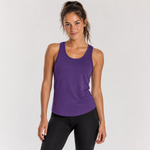 A woman modeling a purple athletic tank top paired with black leggings, standing against a light gray studio background.