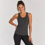A woman modeling a dark gray racerback tank top and black leggings against a light gray studio background.