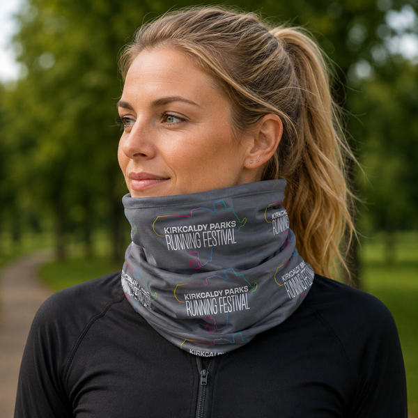A woman wearing a grey neck gaiter with 'Kirkcaldy Parks Running Festival' printed on it, photographed outdoors with a blurred green park background.