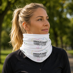 A woman outdoors wearing a white neck gaiter with the text 'KIRKCALDY PARKS RUNNING FESTIVAL' printed on it, paired with a black zip-up top.