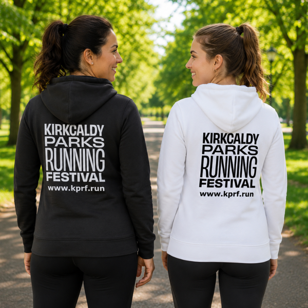 Two women standing on a park path, shown from the back, wearing matching hoodies. The woman on the left wears a black hoodie with white text reading 'KIRKCALDY PARKS RUNNING FESTIVAL' and the website