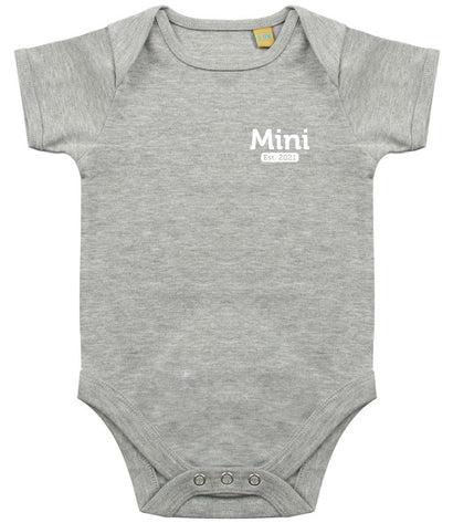 Grey baby onesie with short sleeves, featuring the text 'Mini Est. 2021' in white on the left chest area and snap closures at the bottom.