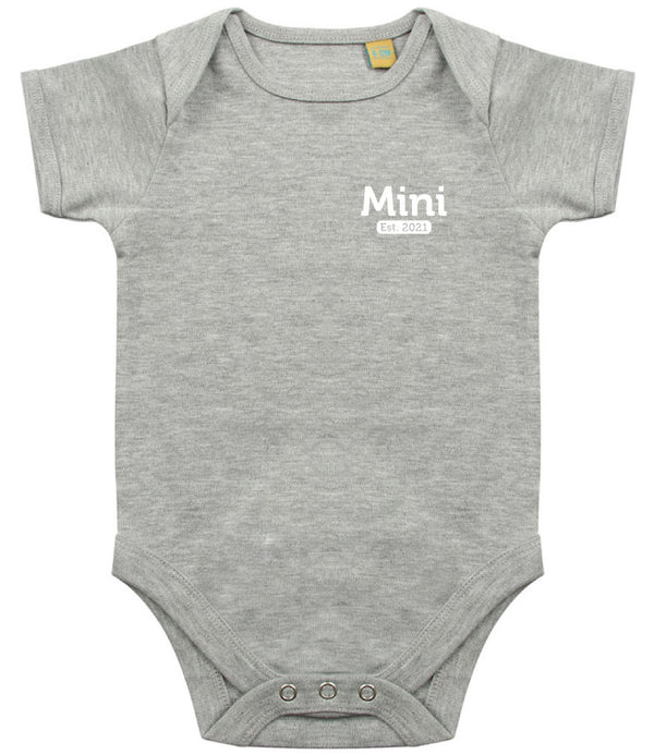 Grey baby onesie with short sleeves, featuring the text 'Mini Est. 2021' in white on the left chest area and snap closures at the bottom.