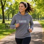 A woman jogging outdoors on a park path wearing a heather grey hoodie with a colourful graphic and the text 'KIF GALDY PARKS RUNNING FESTIVAL' on the chest.