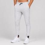 Light grey heather jogger pants worn by a model, featuring an elastic waistband with a black drawstring and side pockets, paired with white sneakers against a light grey studio background.