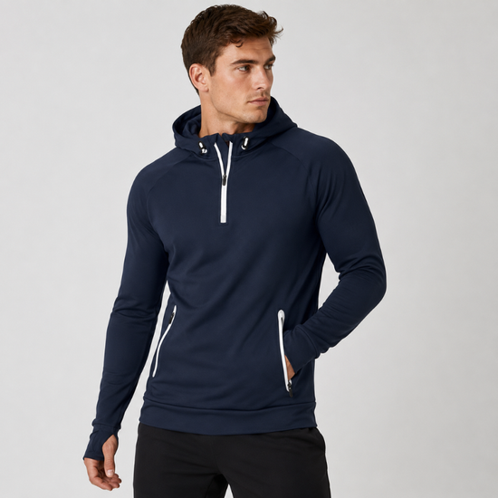 A man wearing a navy blue athletic pullover hoodie with white zipper accents and a drawstring hood, posed against a light gray studio background.