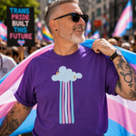 A man wearing a purple t-shirt with a cloud and rainbow graphic, holding a transgender pride flag at a public parade. He is wearing sunglasses and has tattoos on his arms.