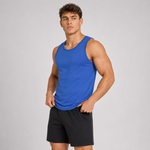 A muscular man wearing a bright blue sleeveless tank top and black athletic shorts, standing against a light gray studio background.