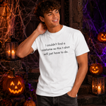 A smiling young man wearing a white graphic t-shirt with the text 'I couldn't find a costume so this t-shirt will just have to do.' posed in a spooky Halloween setting with pumpkins, lanterns, and cobwebs.