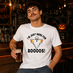 A man wearing a white graphic t-shirt with a Halloween ghost design and the text 'I'M JUST HERE FOR BOOOOS!' while holding a pint of beer in a dimly lit bar setting.