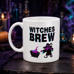 A white ceramic mug with 'WITCHES BREW' printed in black and pink holographic lettering, alongside a witch and cauldron graphic. The mug is set on a dark wooden table with a blurred background of candles, bottles, and purple smoke.